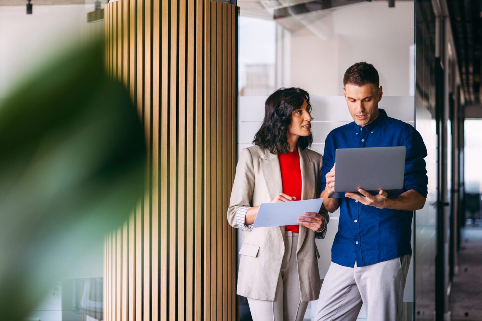 Two professionals discussing work with digital devices in a modern office.
