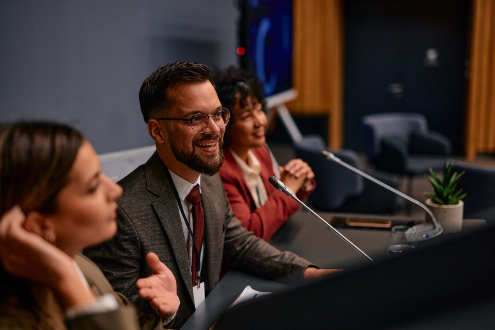 A man smiling while speaking at a conference panel.
