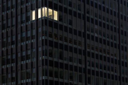Illuminated office window in a dark high-rise building at night.