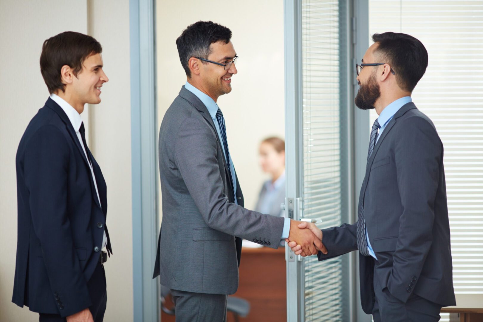 Two businessmen shaking hands in a professional setting.