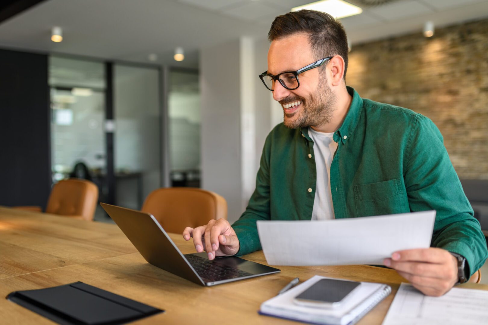 Man working on laptop with documents in office.