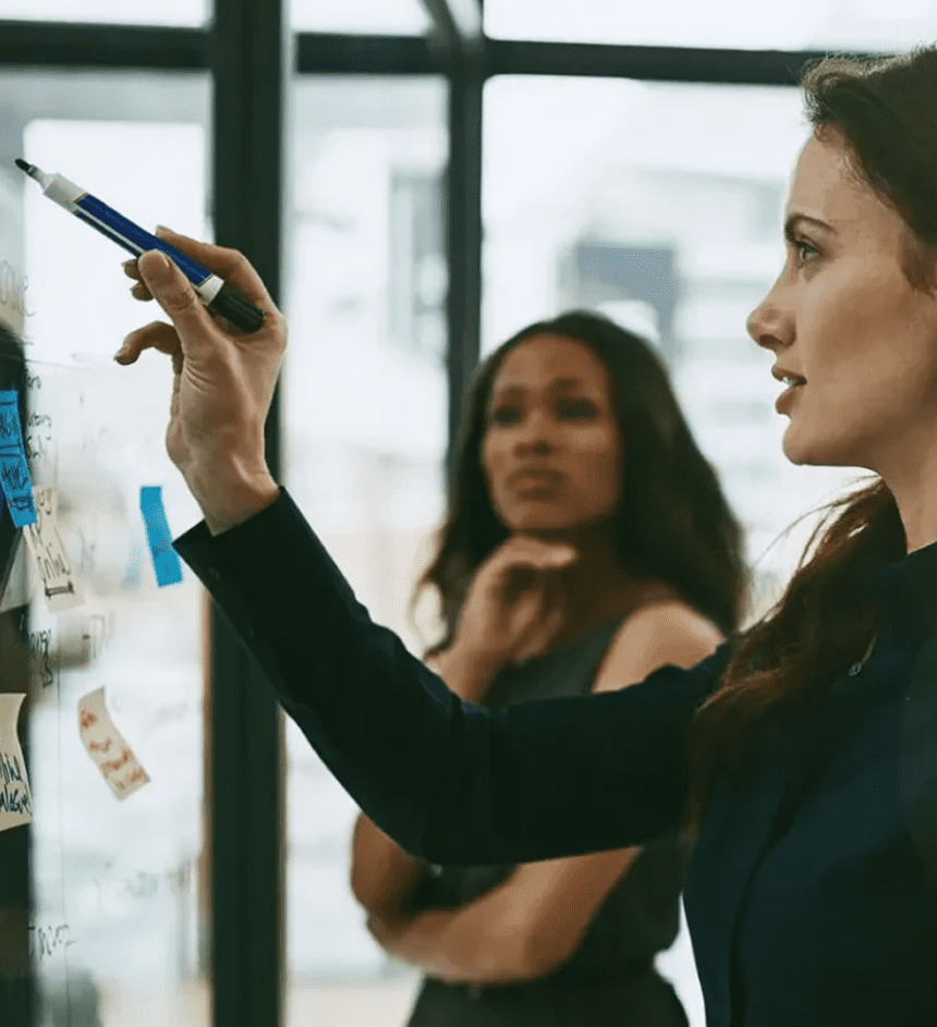 Two women brainstorming ideas on sticky notes in an office.