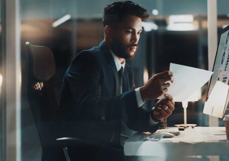A man in a suit working thoughtfully at his desk.