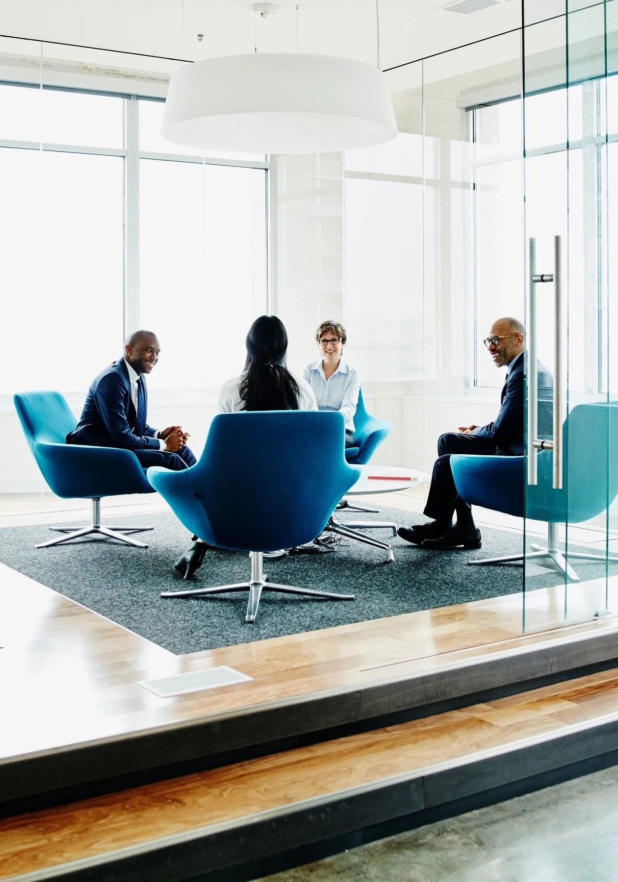 Four professionals in a modern office lounge having a meeting.